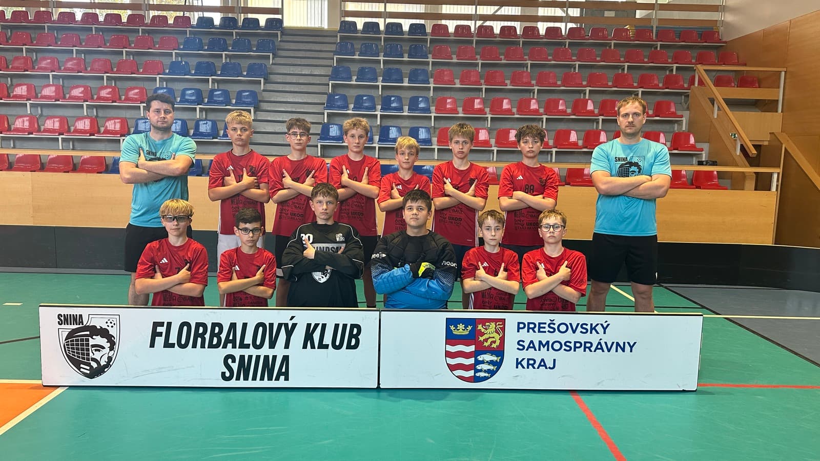 Tím FK Snina s klubovým bannerom v športovej hale