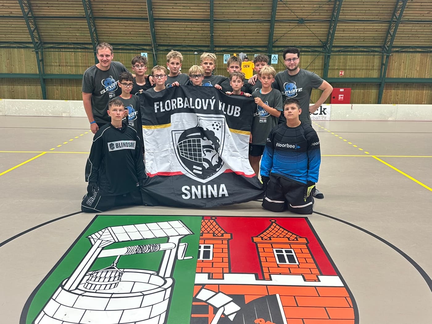 Hráči FK Snina držia klubovú vlajku s logom florbalového klubu