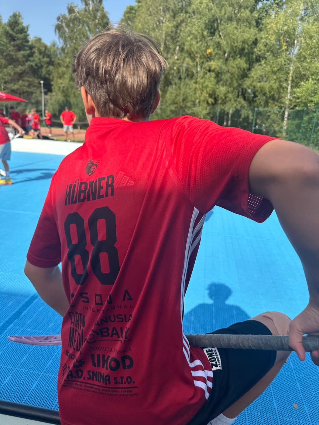 Hráč FK Snina v červenom drese s číslom 88 sleduje florbalový zápas